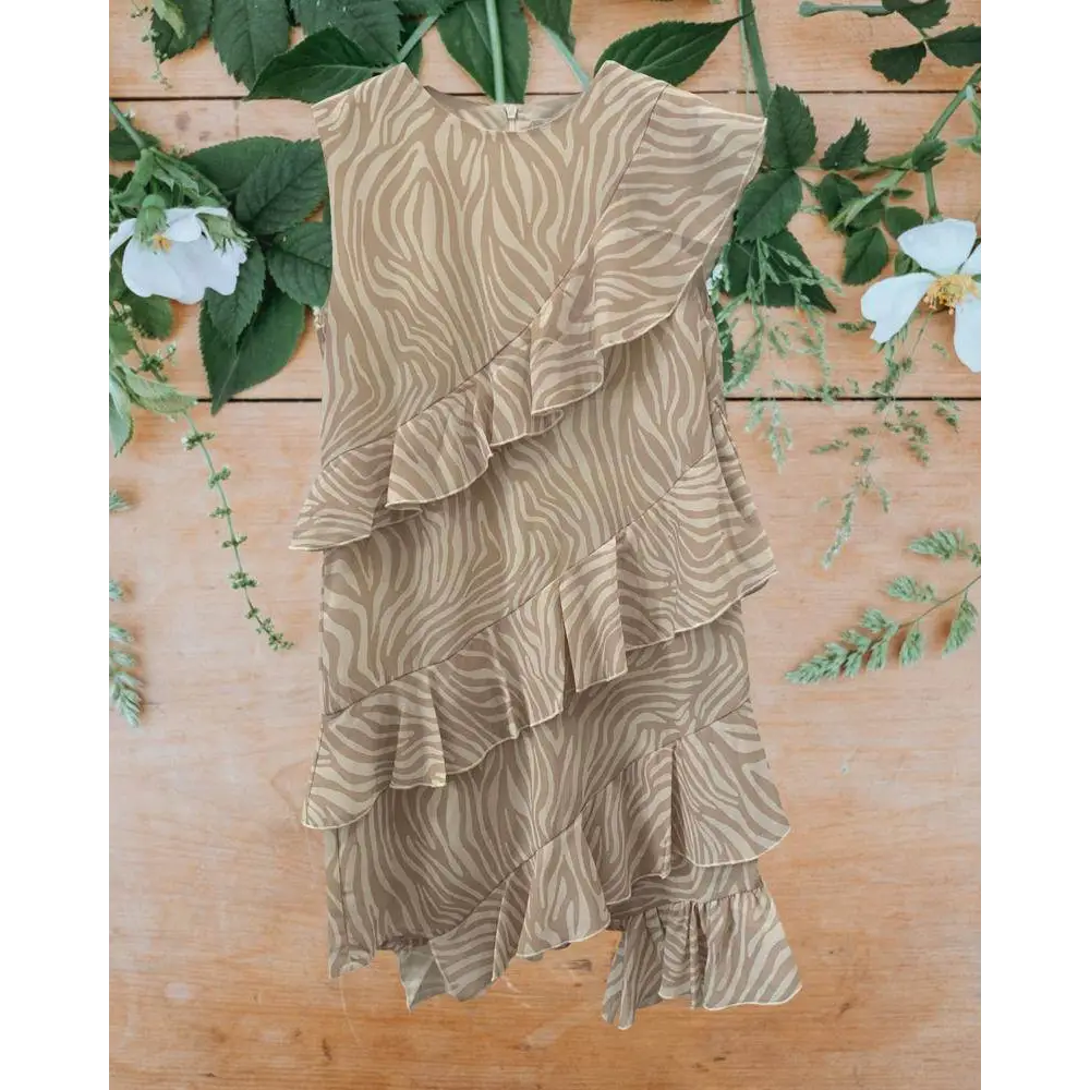 abito bambina stampa zebrata in chiffon beige con balze a volant asimmetrico su sfondo legno e foglie