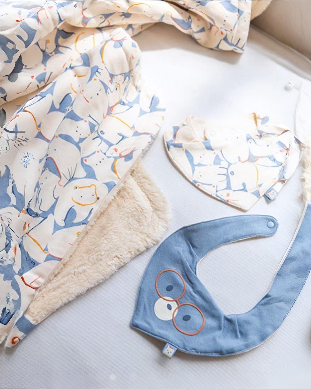 Bavaglino per neonato a maglia con animali azzuro Boboli accanto a copertina e bavaglino a triangolo con stampa animaletti