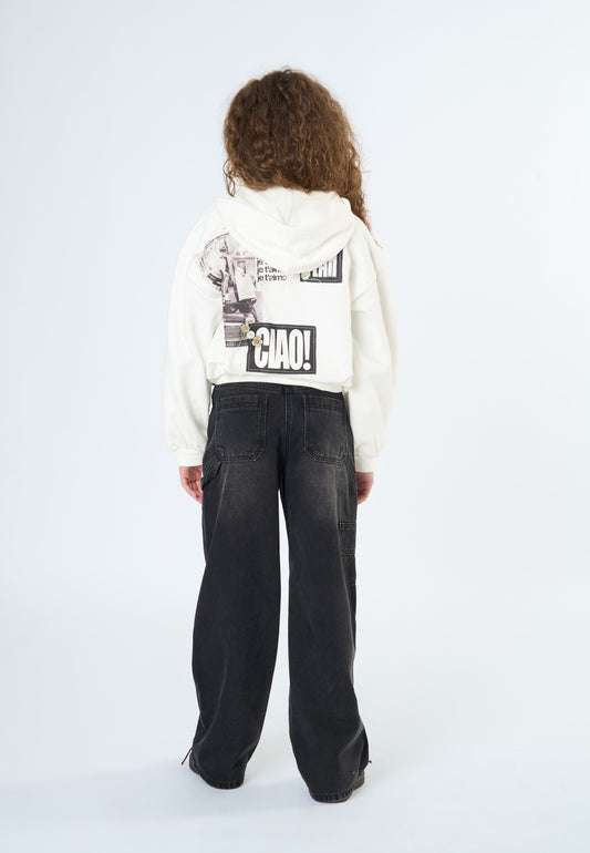 Jeans neri larghi ragazza abbinati a una felpa bianca con stampa retro, look moderno e casual