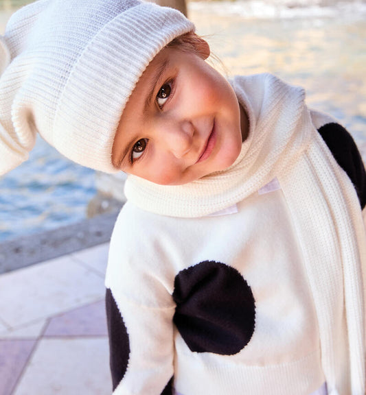 Bambina sorridente sulle rive con sciarpa e cappello bambina in maglia bianca Sarabanda abbinati