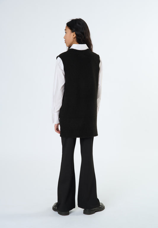 Pantaloni neri a zampa ragazza abbinati a un gilet nero per un look elegante e moderno