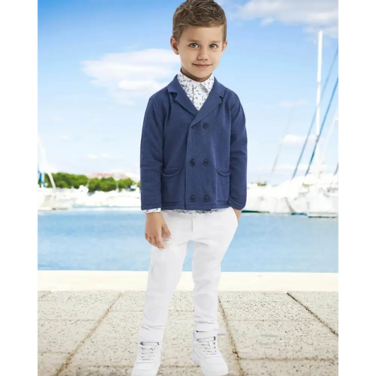 Cardigan bambino Sarabanda blu doppiopetto indossato da bambino con camicia fantasia e pantaloni bianchi sul molo