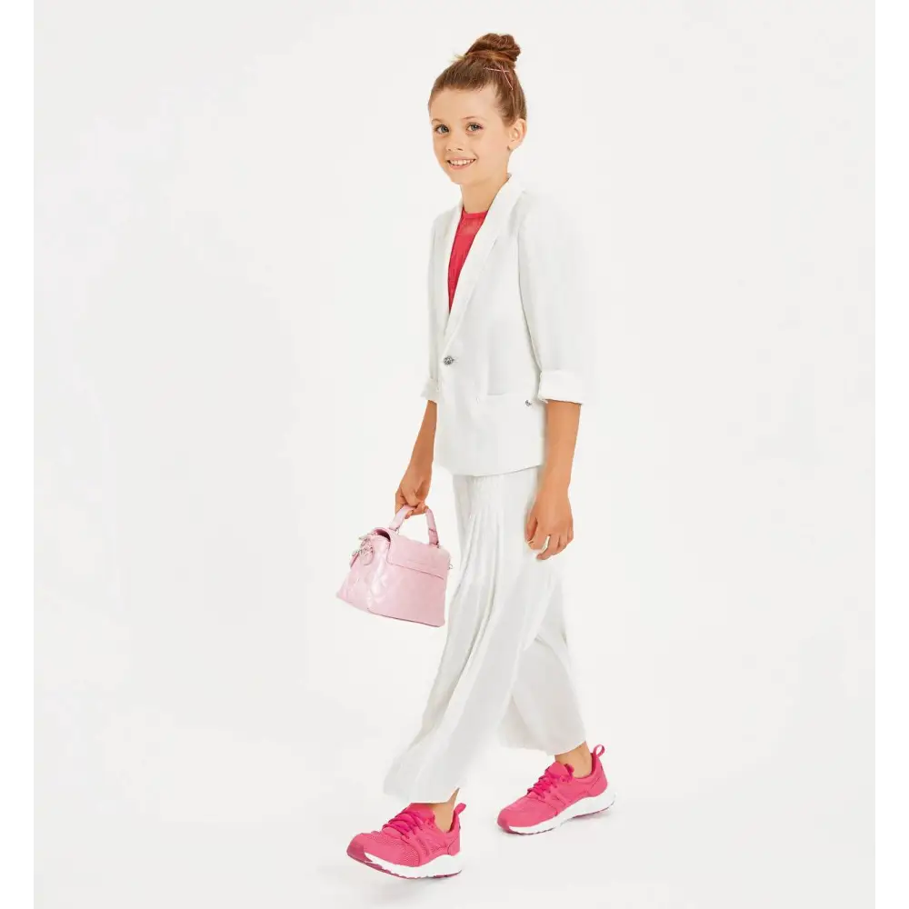 Ragazza che indossa pantaloni plissettati bambina Sarabanda bianchi con giacca coordinata e sneakers rosa
