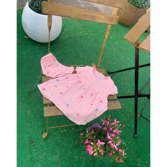 Vestito rosa neonata floreale Boboli con maniche corte e spillettina coordinata su sedia in legno