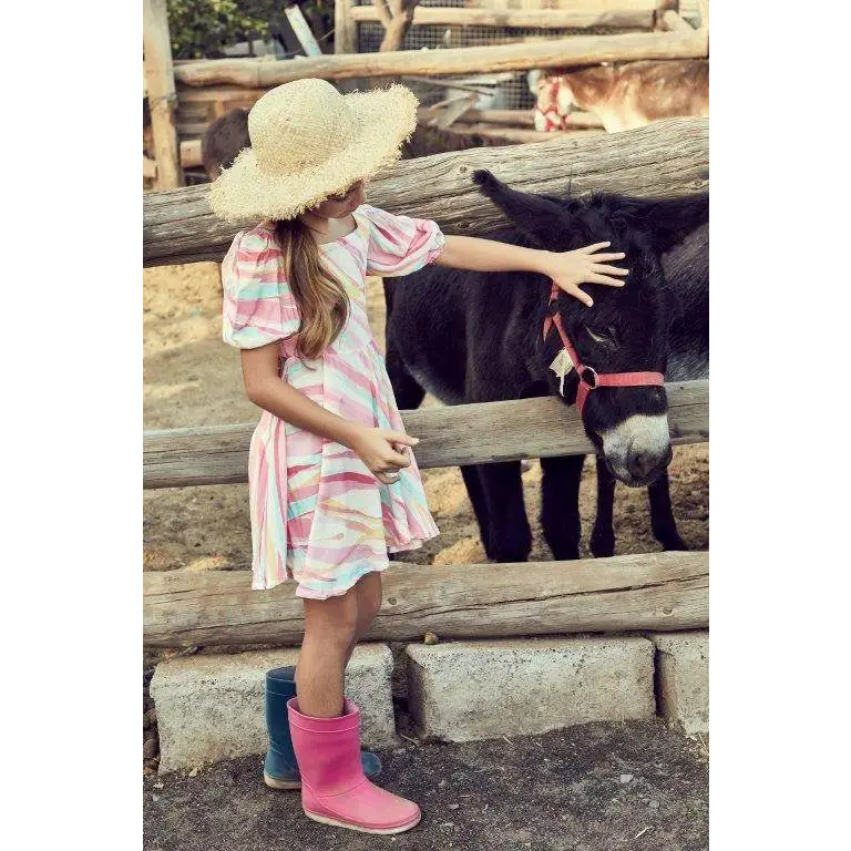 Ragazza con cappello di paglia che accarezza un asino indossando abito colorato bambina 8-16 anni e stivali di gomma
