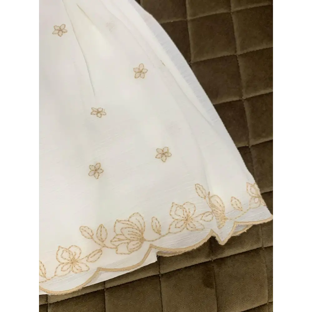 Dettaglio orlo abito cerimonia con culotte bianco con ricami floreali dorati Mayoral