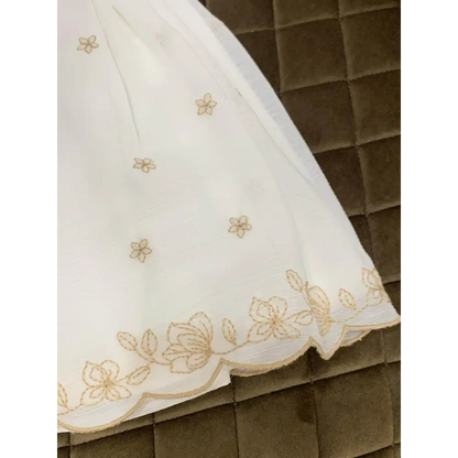 Dettaglio orlo abito cerimonia con culotte bianco con ricami floreali dorati Mayoral