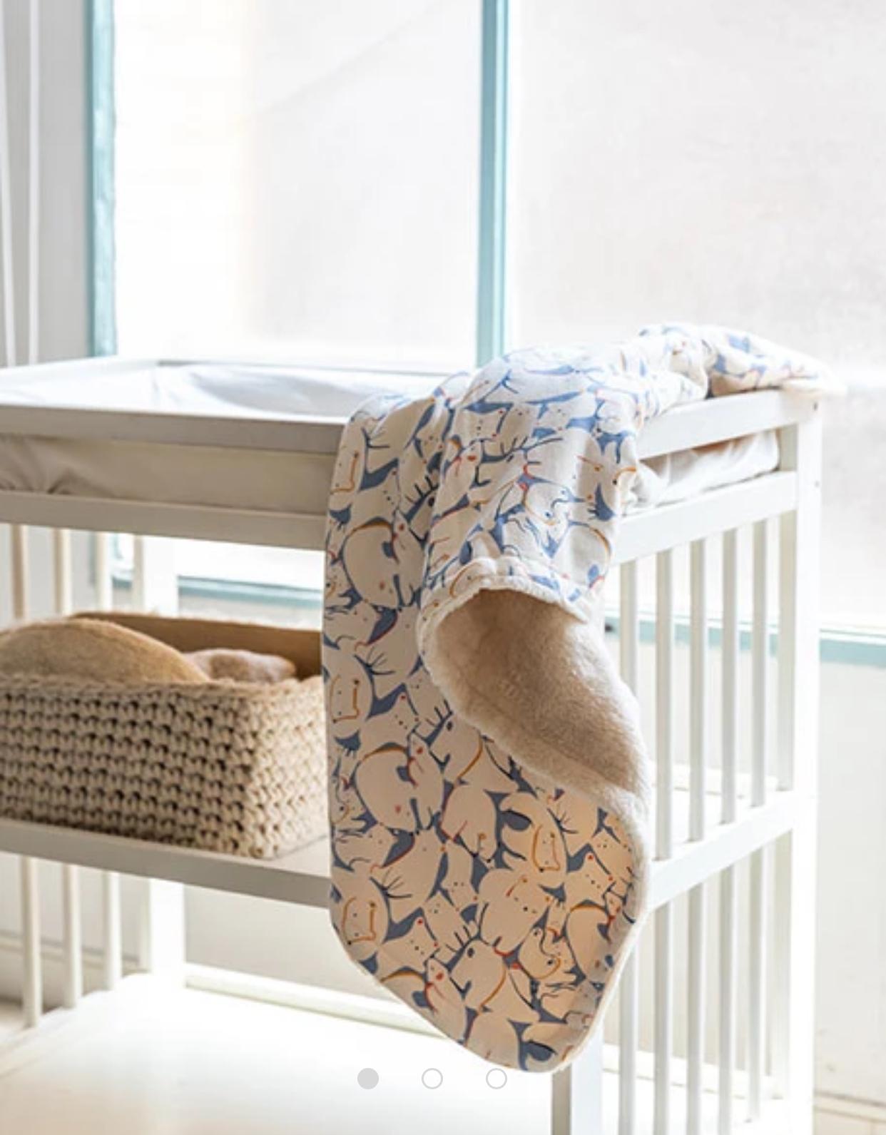 Copertina per neonato in pile stampato con animali nei toni del blu e beige posata su fasciatoio bianco Boboli