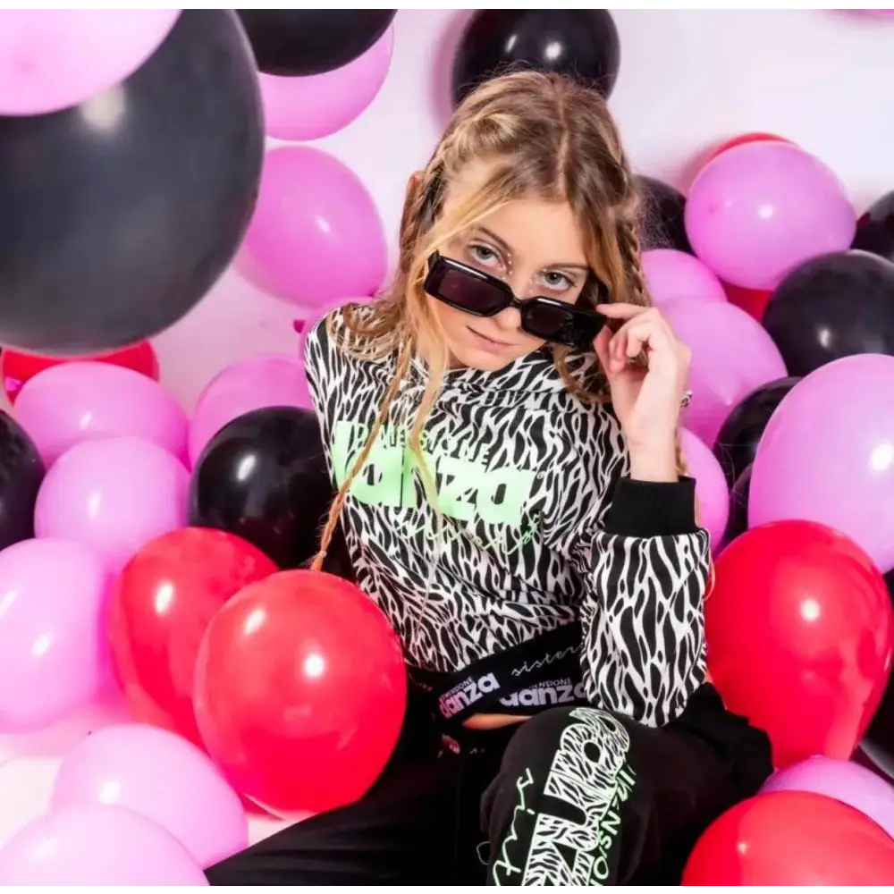 Ragazza con occhiali da sole tra palloncini indossa pantaloni ragazza Dimensione Danza neri con stampa verde fluo