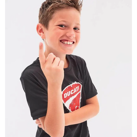 Ragazzo sorridente in t-shirt Ducati bambino nera con logo rosso e bianco, cotone casual a maniche corte