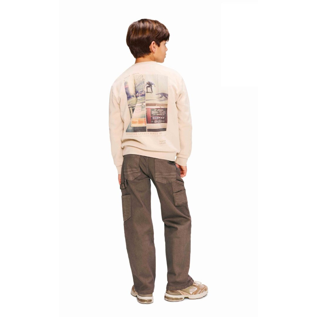 Ragazzo che indossa jeans ragazzo Retour oversized ruggine in denim stretch con vita regolabile e felpa con stampa sul retro