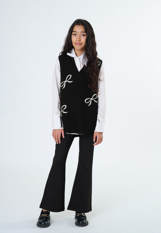 Ragazza che indossa pantaloni neri a zampa con top nero e camicia bianca, look elegante e alla moda