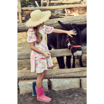 Ragazza con cappello di paglia che accarezza un asino indossando abito colorato bambina 8-16 anni e stivali di gomma